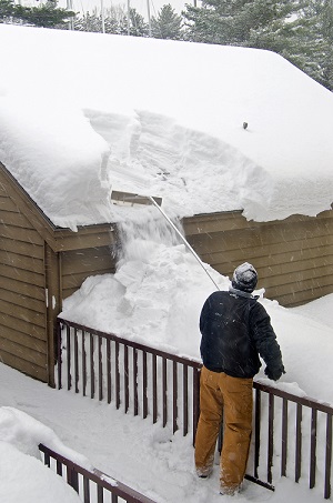 Man-removes-snow-from-roof-with-roof-rake
